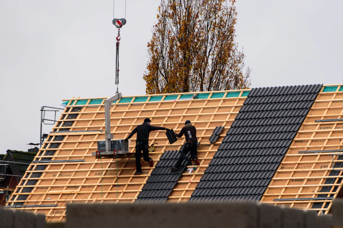 Roofers installing interlocking roof tiles over timber battens