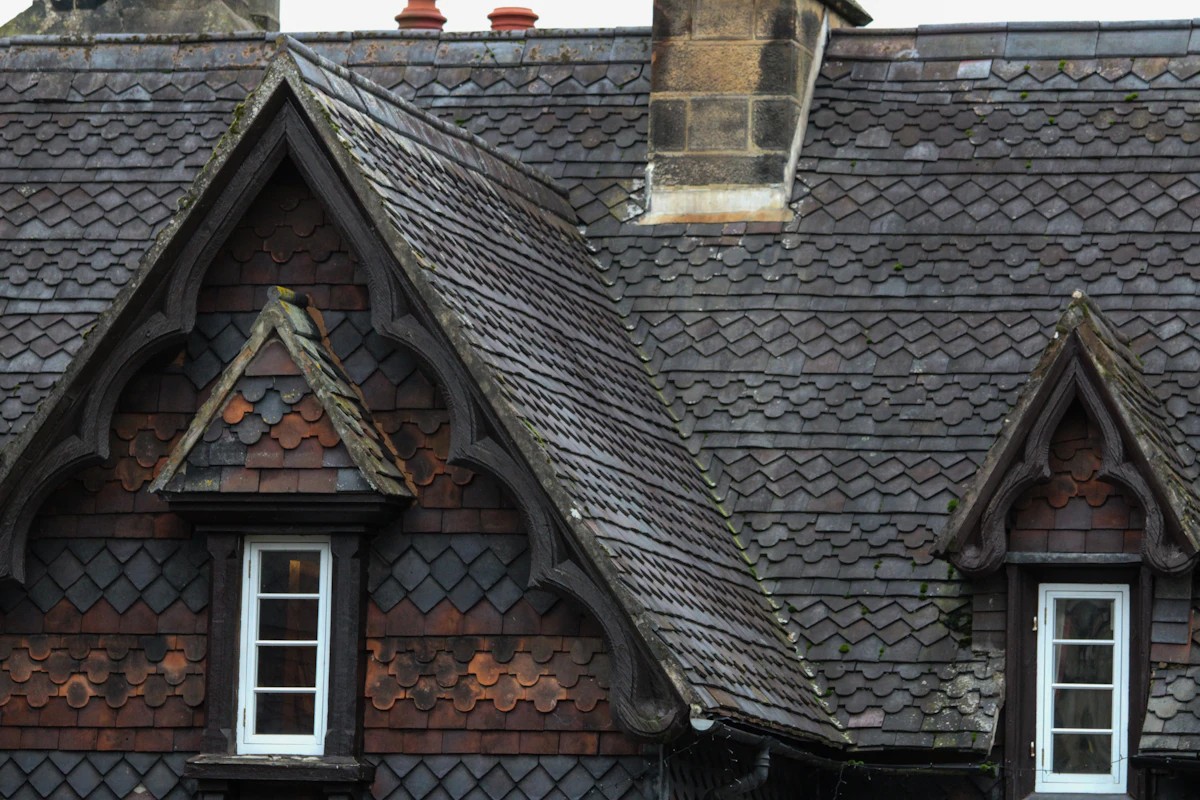Decorative slate roof with two dormer windows and a stone chimney