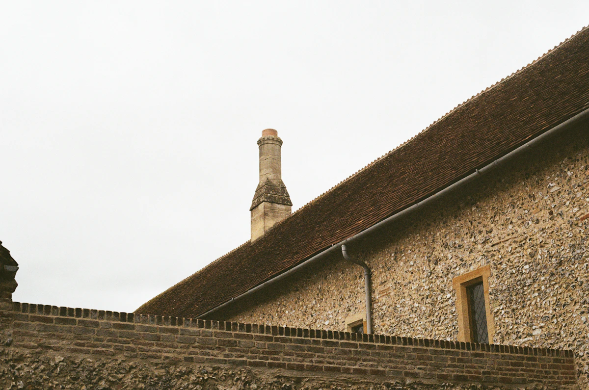 Clay tile roof, stone chimney and gutter on a historic stone building